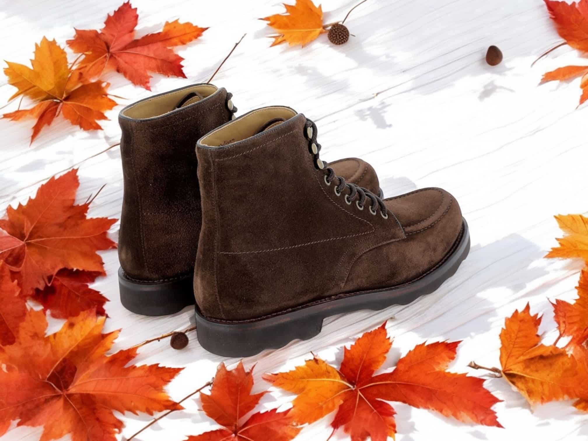 Bottes marron avec feuilles d'automne autour.