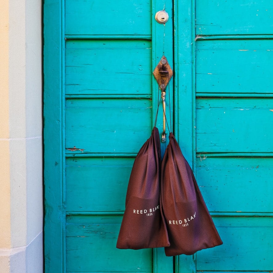 Deux sacs suspendus à une porte verte.