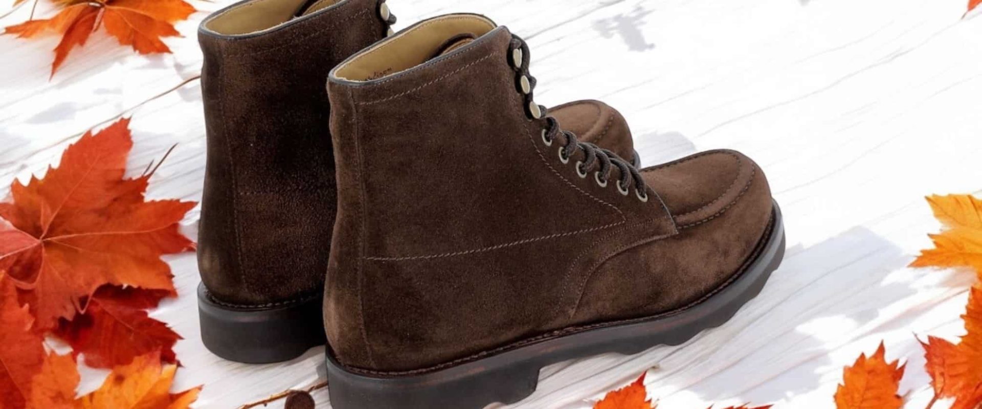 Bottes marron avec feuilles d'automne autour.